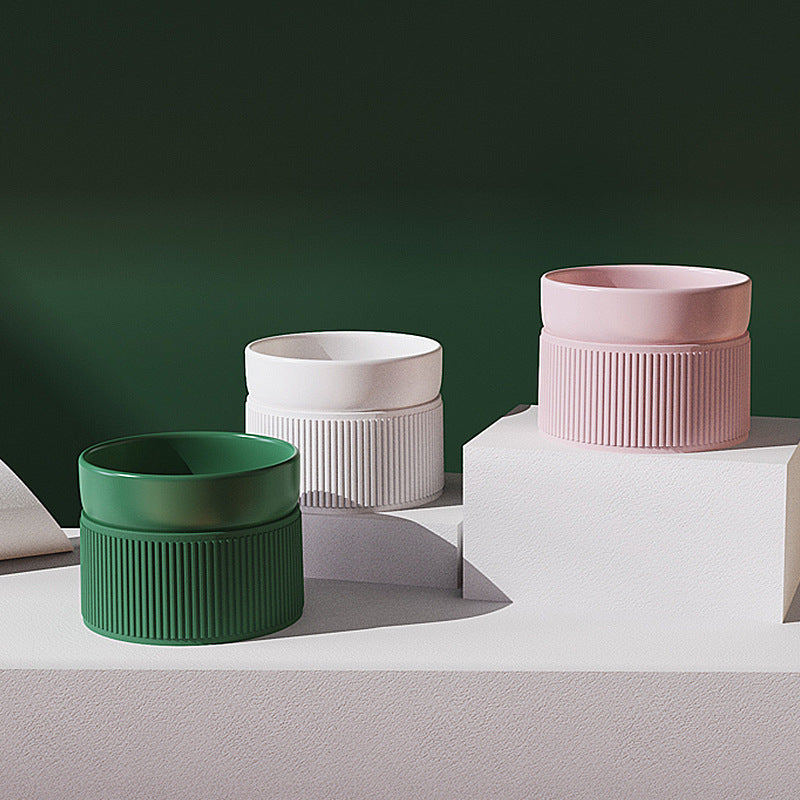 Three ceramic pots in green, white, and pink on a white platform with a dark green background