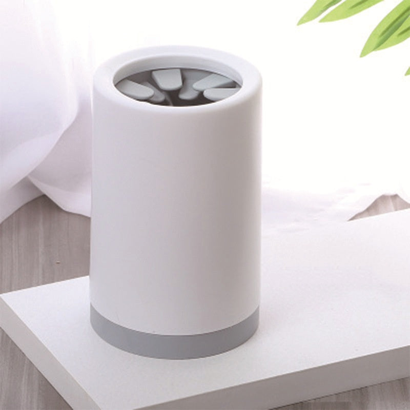 White and gray cylindrical paw cleaner on a white surface with a blurred background