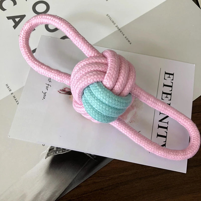 Pink knotted rope toy with a green ball on a magazine page