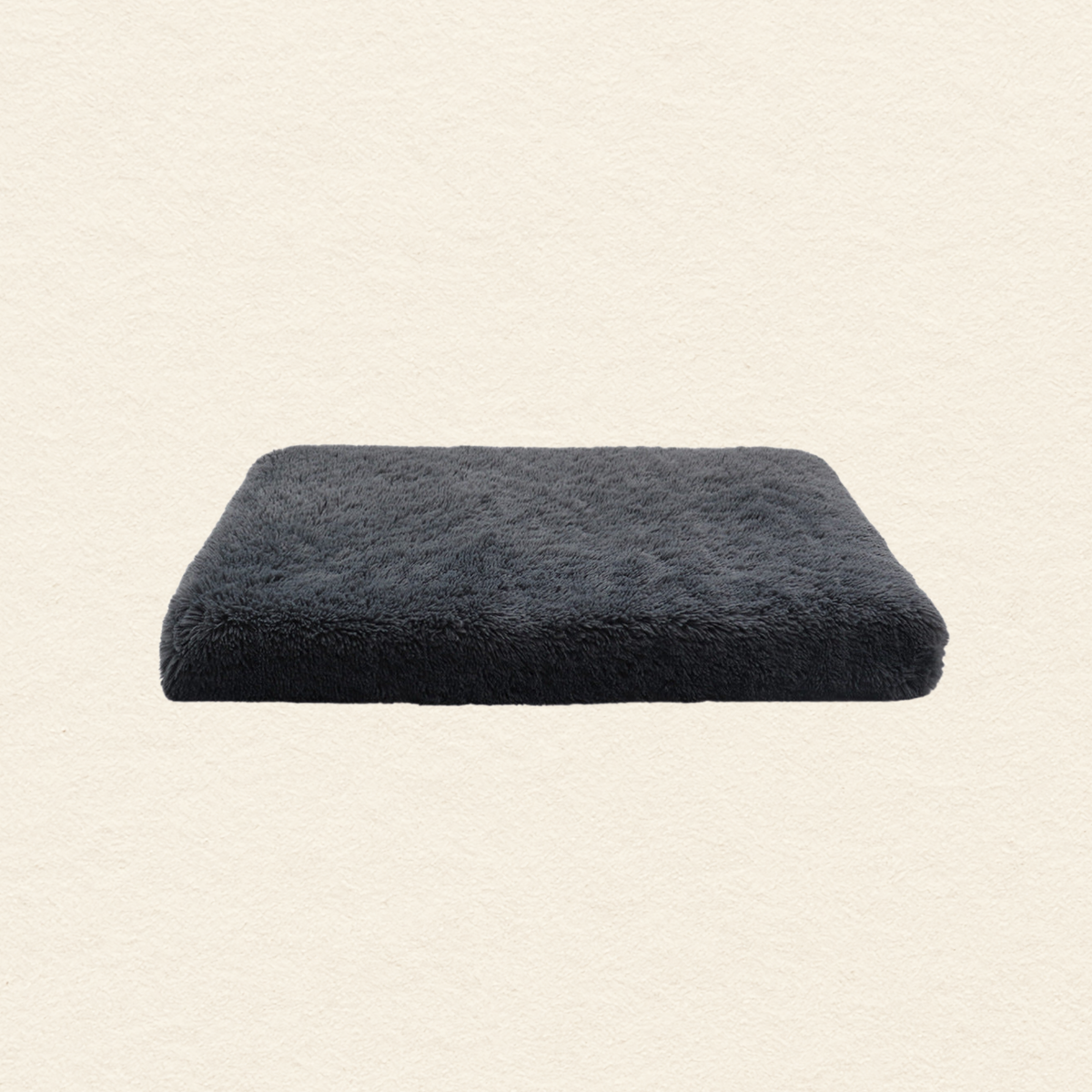 A rectangular dark charcoal gray plush bath mat shown against a textured off-white background.