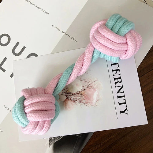 Pink and blue knotted rope toy on a magazine