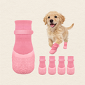 Pink dog booties shown on a light cream background, with one large bootie on the left, four smaller booties aligned at the bottom, and a small golden puppy wearing all four on the right.
