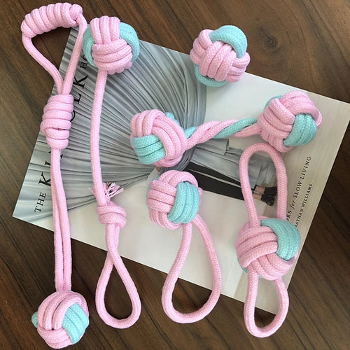 Pink and teal knotted dog toys on a magazine