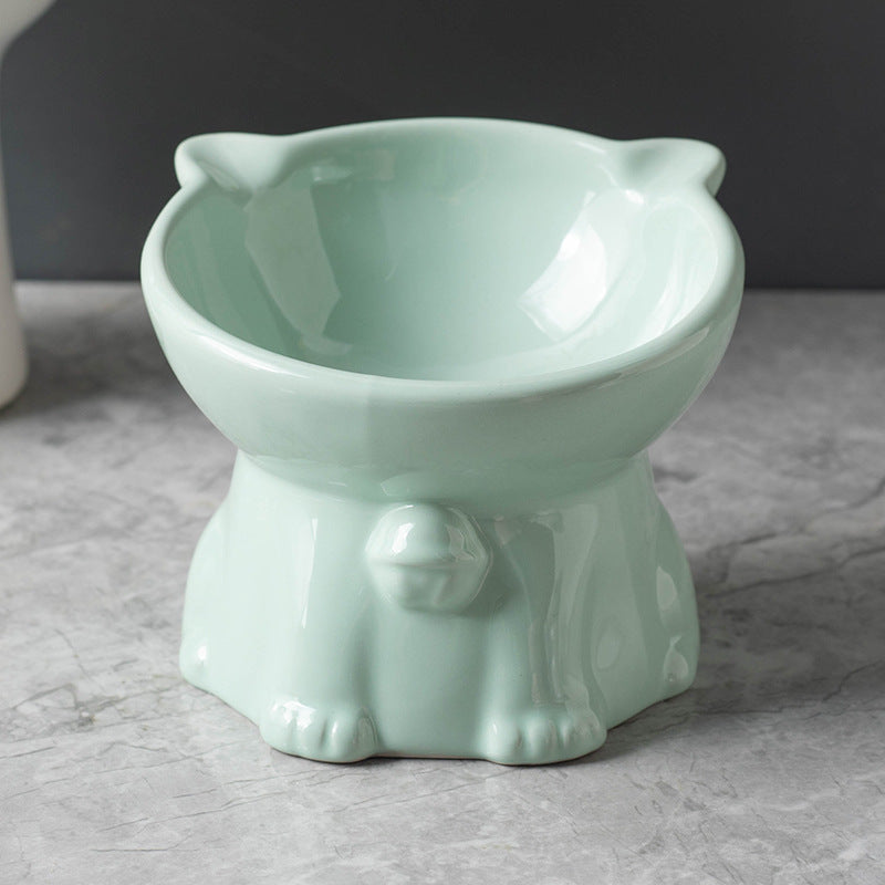 Light green ceramic cat shaped bowl on a stand with a dark background