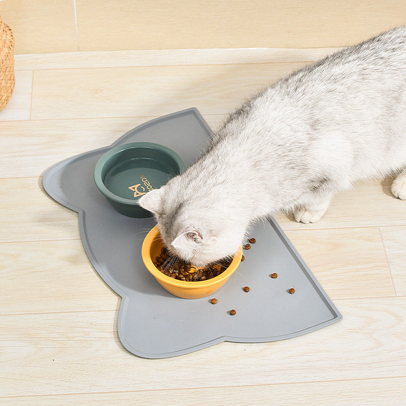 Cat eating from a bowl on a gray mat